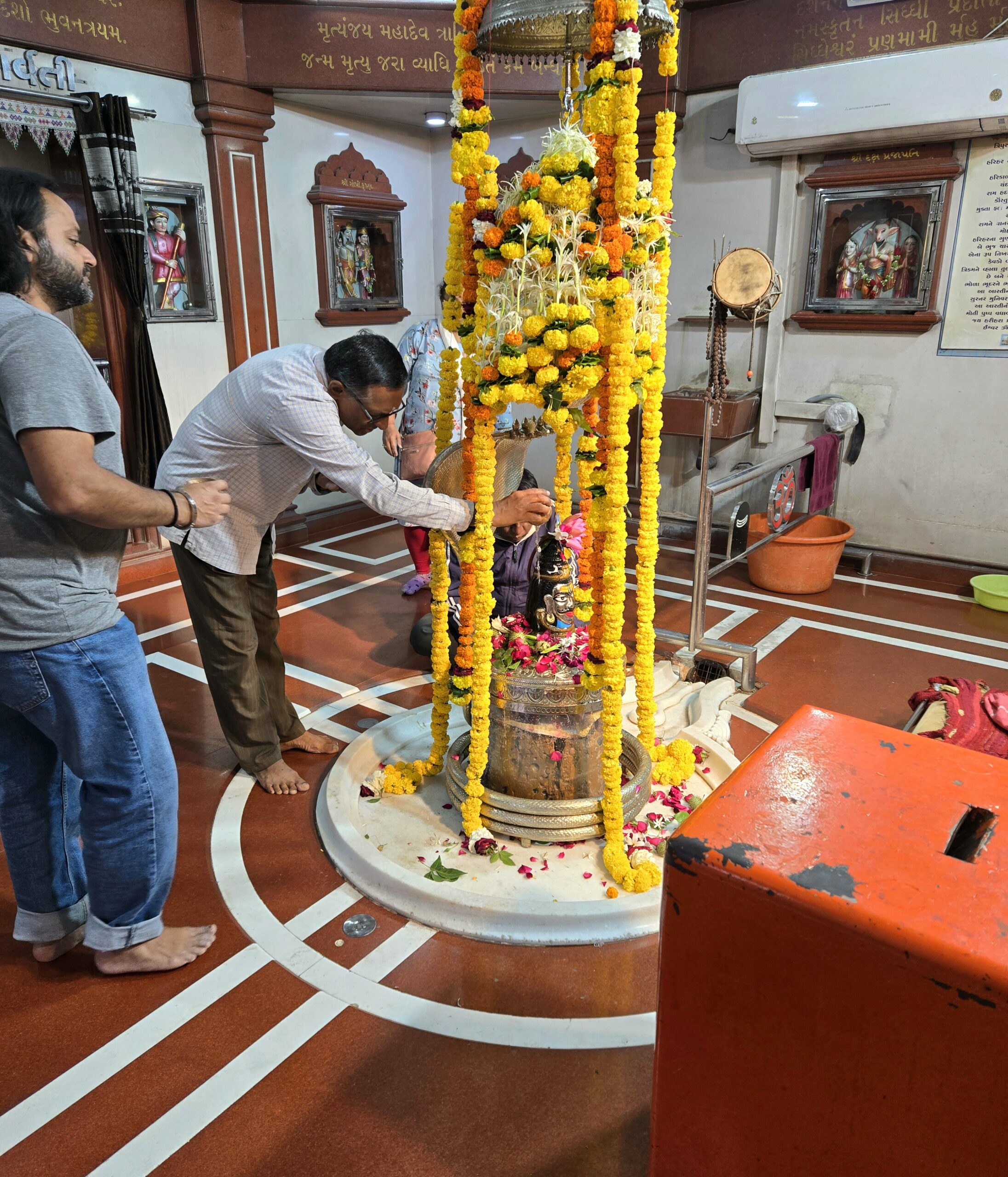 A devotee making an offering at the flower-covered Shiva linga inside Shree Siddhnath Mahadev Mandir
