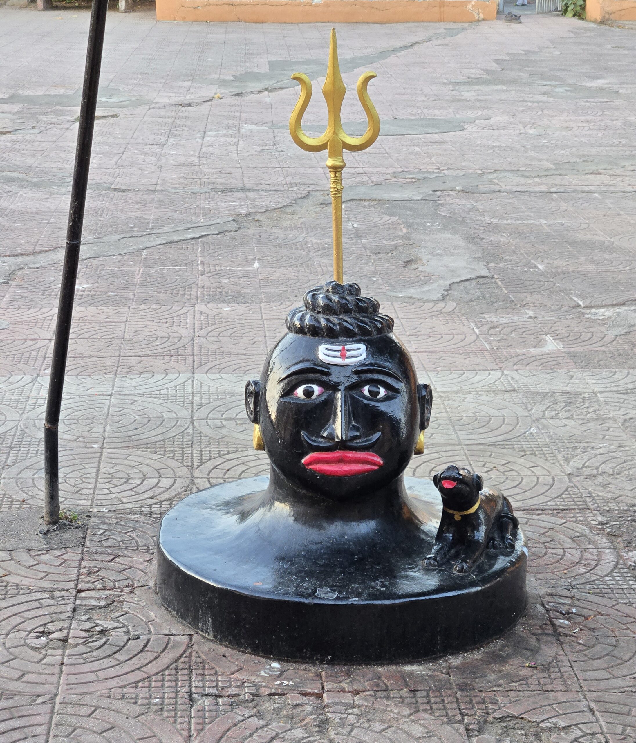 Kaal Bhairav, a form of Shiva Bhagwan, beneath a golden trishul with his dog companion