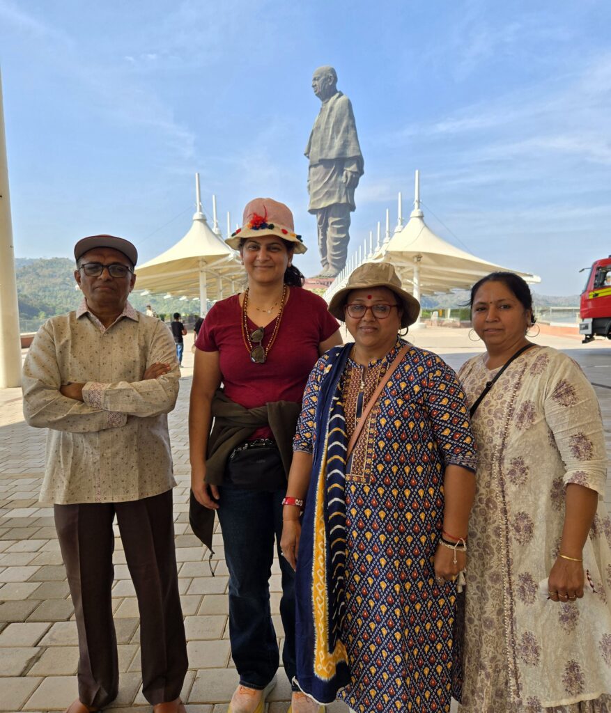 Ruby and Kapi maasi in playful travel hats posing with family beneath the Statue of Unity